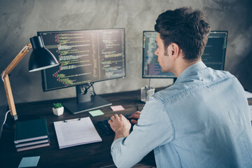 Rear back behind view portrait of his he nice attractive focused geek guy typing css analyzing cyberspace security building at modern industrial interior style concrete wall work place station