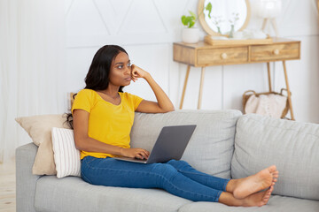 Wall Mural - Serious black female student with laptop thinking over complicated online task during her remote studies at home
