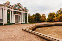 An Old Building With Columns In An Autumn Park Against A Background Of Red Leaves.