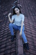 © AndhikaRaya - The blonde girl sits on the roof tile while stylishly wearing a gray shirt. female t-shirt models for mockups and templates.