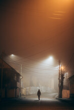Woman Walking Alone In Foggy City At Night