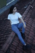 © AndhikaRaya - The blonde girl sits on the roof tile in a style wearing a white t-shirt. female t-shirt models for mockups and templates.