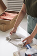© AnnaStills - Close-up of woman standing at the table packing new blouse into the box before delivering