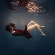 © Dmitry - A girl with long hair in a red lace dress swims underwater as if in zero gravity