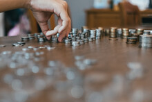 Cropped Hand Of Person Stacking Coins On Table