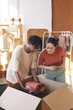 © AnnaStills - Two young people working in team they putting new clothes into the cardboard box and preparing parcel for delivery in warehouse