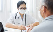 © eggeeggjiew - Asian woman Doctor wear eyeglasses and face mask giving advice to Elderly patient