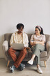 © AnnaStills - Multiethnic couple sitting on sofa with laptop and paying with credit card for their online purchases