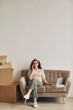 © AnnaStills - Young successful woman sitting on sofa with laptop she accepting orders by the phone with big stacks of parcels near the sofa prepared for delivering