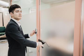 a new manager opens the door to his office in a strict business suit, Caucasian appearance, short hairstyle, strong barbershop