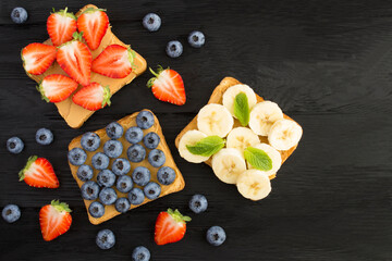 Wall Mural - Top view of sandwiches  with peanut butter and fruit on the black wooden surface