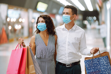 Beautiful young loving couple holding shopping bags and enjoying together purchases in mall. Consumerism, purchases, love, sales, Black friday concept.