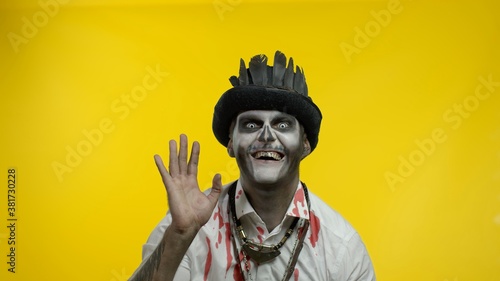 Fotografía Sinister man with professional Halloween skeleton makeup greeting someone, say h