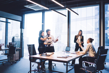 Business people using gadgets and reading documents at meeting