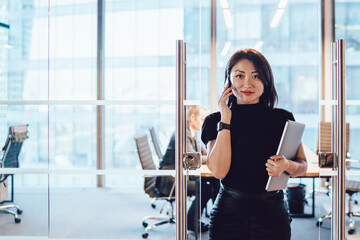 Delighted female executive manager making phone call in contemporary workspace