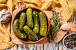 Marinated cucumbers gherkins in wooden plate. Pickles with mustard and garlic. White background. Top view