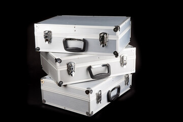 a stack of three shiny aluminum equipment cases isolated on black