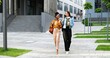 © VAKSMANV - Mixed-races young pretty females, best friends talking cheerfully and walking with cups of coffee to-go and at city street. Multi ethnic beautiful happy women students strolling outside with drinks.
