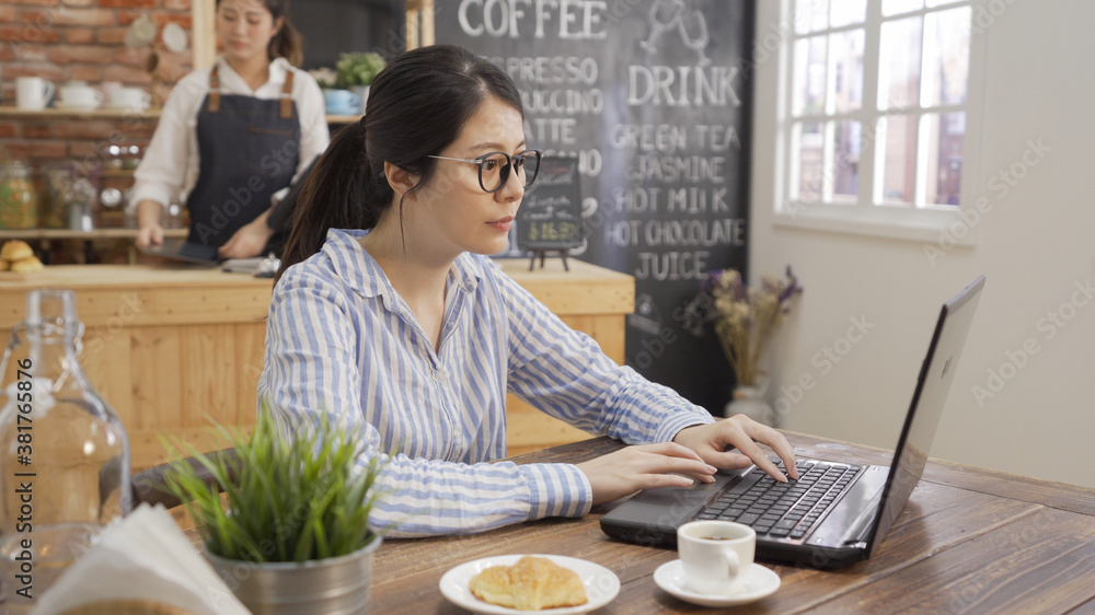 Young business woman sitting at table and taking notes in notebook ...