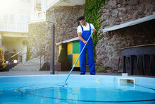Worker Cleaning Outdoor Swimming Pool With Underwater Vacuum