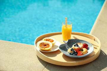 Tray with delicious breakfast near swimming pool