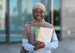© Prostock-studio - Education For Muslim Women. Smiling african islamic female college student posing outdoor