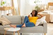 © Prostock-studio - Lovely millennial black woman chilling on couch with cup of hot beverage at home