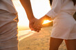 © New Africa - Lovely couple holding hands on beach at sunset, closeup