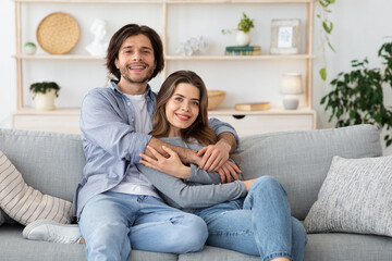 Wall Mural - Happy married couple hugging on couch at home