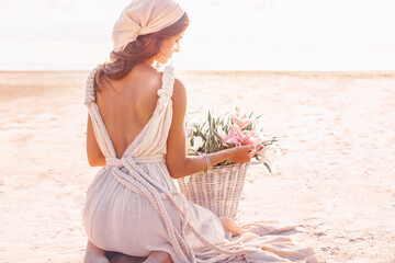 Wall Mural - beautiful young stylish woman with basket with flowers outdoors at sunset