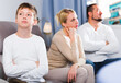 © JackF - Upset son and frustrated parents sitting on sofa and looking away after quarrel