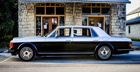 Side view of luxury, two toned, classic, vintage car parked in a small historic downtown