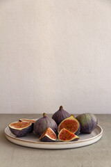 Wall Mural - Fresh figs on a plate on a light concrete background