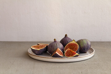 Wall Mural - Fresh figs on a plate on a light concrete background