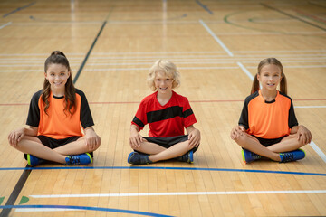 Wall Mural - Kids in bright sportswear sitting in lotus pose