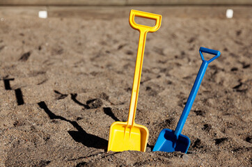 two toy shovels in the sandbox