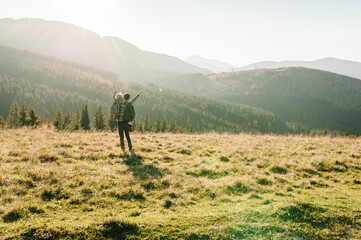 The daughter hug father on nature. Dad with backpack and child walk in the autumn grass. Family spending time together in mountain outside, on vacation. Holiday trip concept. World Tourism Day.