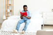 © Pixel-Shot - African-American man reading book at home