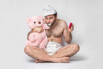 Infant adult man with pacifier in diaper holding pink teddy bear