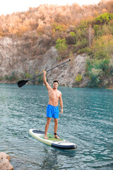 Wall Mural - Young man using paddle board for sup surfing in river