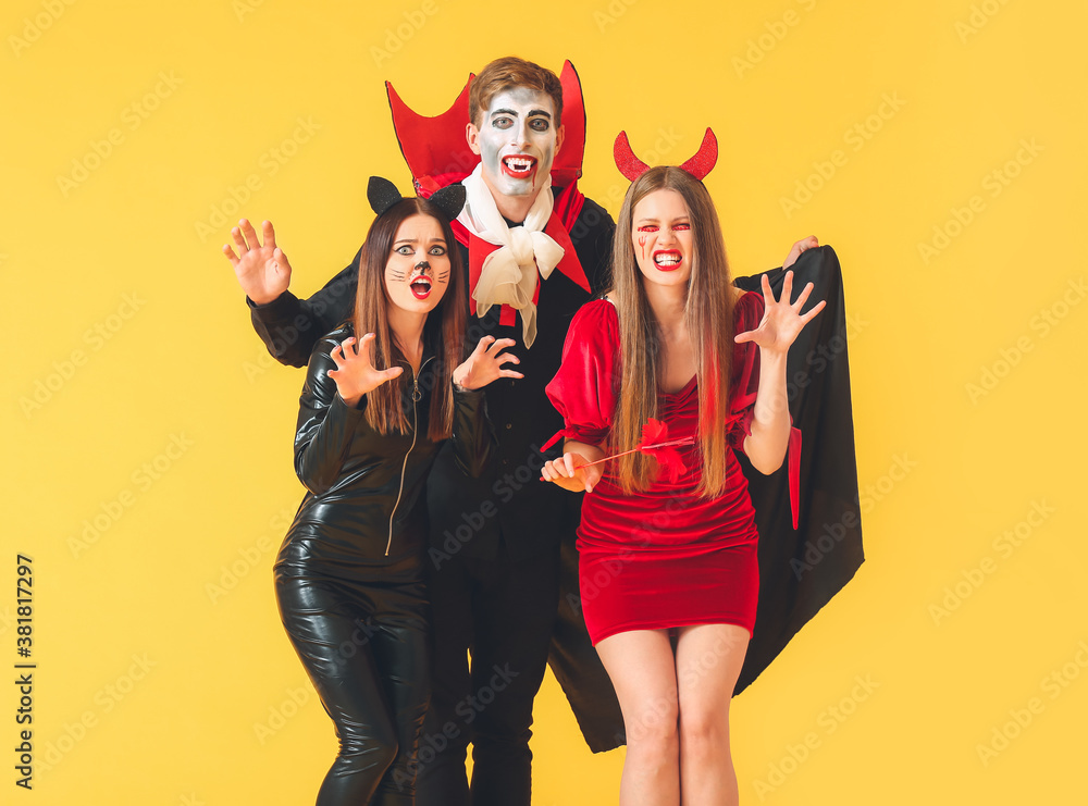 Friends in Halloween costumes on color background