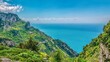 A panoramic view of the steep, terraced vineyards and dramatic coastline of the Amalfi Coast in Italy, as viewed from the Path of the Gods hiking trail.