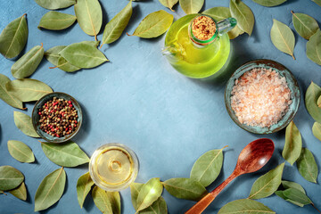 Wall Mural - Cooking background with copy space. Salt, pepper, bay leaves, olive oil and white wine, shot from the top on a blue background