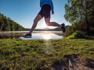 Man or boy is running at lake in summer morning