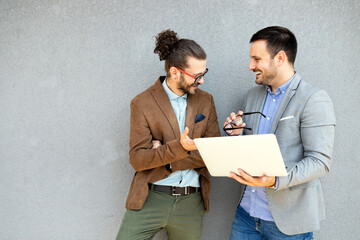 Cheerful happy businessmen using laptop at the meeting outdoor