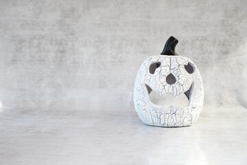 Halloween background with sculpture gray pumpkin with big smile on white gray concreate or cement wall background and space for write text on, decorate  or inviting halloween concept.