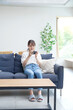 © siro46 - ソファーでスマートフォンを使う女性