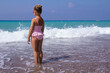 © Irina - Little girl in a pink bathing suit and pink glasses on the beach. He stands with his back to the waves. Her hair is in a bun
