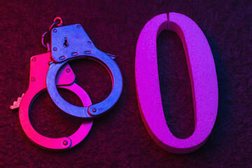 Handcuffs and number zero on a stone surface close-up. Concept on the topic of zeroing prison terms