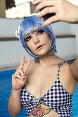 Sticker - Vertical shot of a European female with blue hair taking a selfie at swimming pool